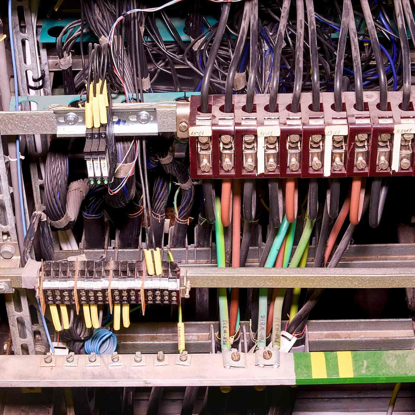 A close-up view of an electrical panel with various colored wires connected to terminal blocks and switches, showing a complex arrangement of cables and electrical components.